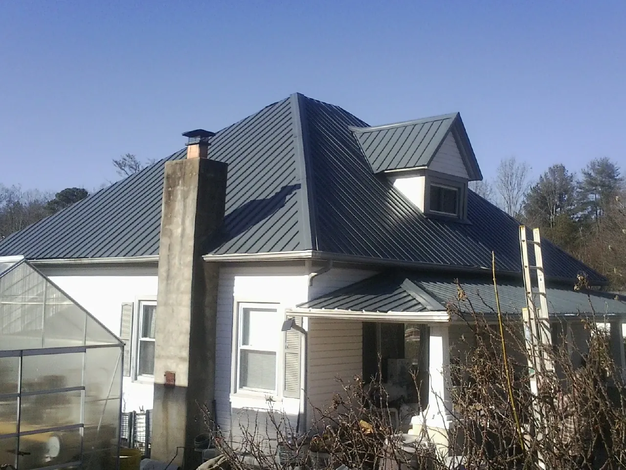 Dark blue standing seam metal roof on a white farmhouse with dormer — Slate & Tile Roof Repair by Roofing Brothers in Leola