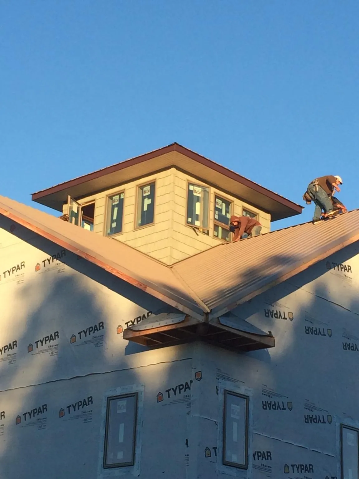 Roofers working around a rooftop cupola on a new metal roof at sunset — Roof Waterproofing in Leola by Roofing Brothers